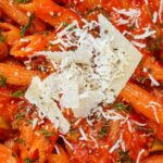 delicious penne pasta topped with grated cheese in macro shot
